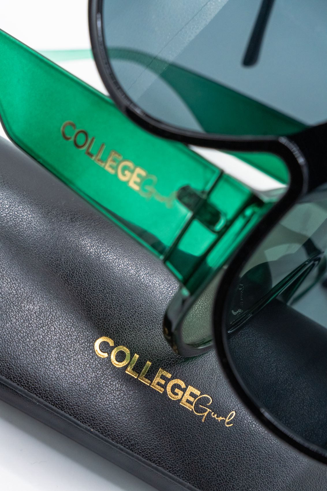Green College Gurl sunglasses resting on the College Gurl case
